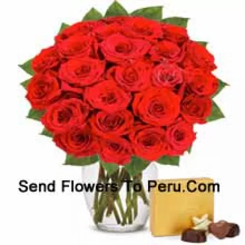 30 roses rouges avec quelques fougères dans un vase en verre accompagnées d'une boîte de chocolats importés